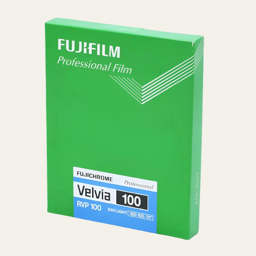 Green packaging of Fujifilm Velvia 100 film on a light blue background
